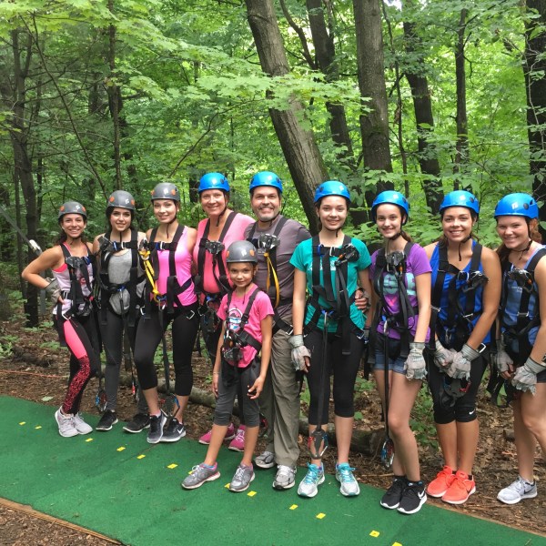 Group of people in helmets and harnesses stand in a forest.