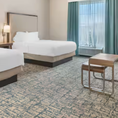 Hotel room with two beds, sofa, TV, and modern decor