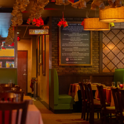Cozy, dimly lit restaurant interior with wooden tables, chairs, and decorative ceiling lights.